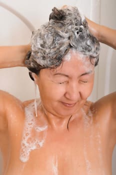 Asian woman showering and washing her hair with shampoo