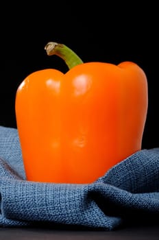 A orange bell pepper isolated over black