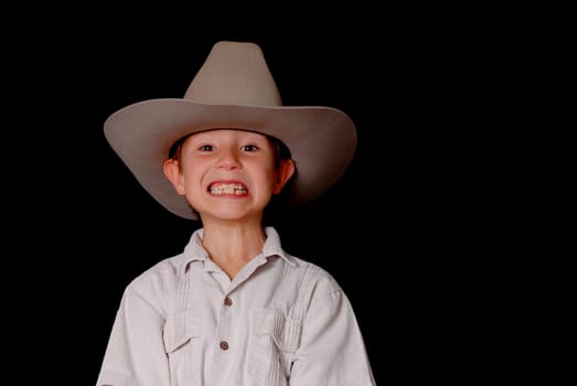 Young boy wearing a cowboy hat isolated on black