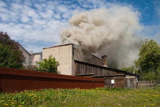 fire in city building, with white smoke to the blue sky