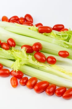 Fresh long green vegetable and small oval red fruit mix on white at an angle.