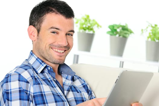 attractive relaxed and positive man is surfing on his tablet