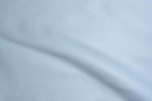 Close-up of light blue fabric with gentle folds and smooth texture, creating a minimalistic background.