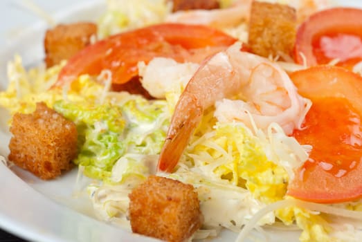 Salad of tiger shrimps, lettuce, chinese cabbage, tomato, garlic rusk, parmesan cheese and sauce