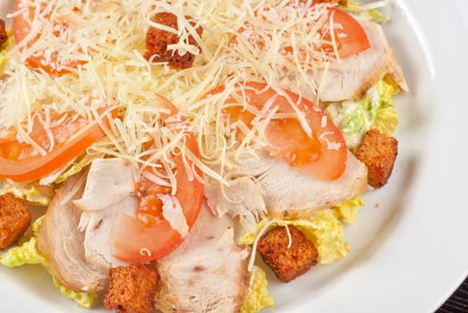 Salad of lettuce, chinese cabbage, tomato, garlic rusk, parmesan cheese, sauce and chicken meat