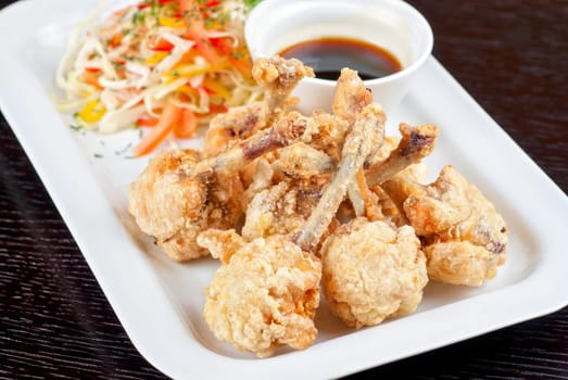 Fried chicken wings garnished with fresh vegetables with Teriyaki sauce