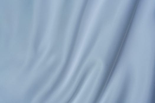 Close-up of soft white fabric with gentle folds creating a swirl pattern, perfect for backgrounds, textures, and design projects.