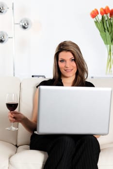 beautiful woman on sofa with computer and glass of wine