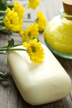 Soap and yellow flowers on wooden table