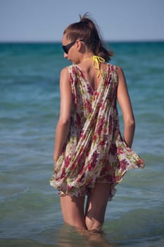 woman in sommer dress standing in water at the beach