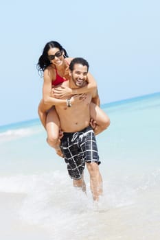 happy maried adult couple having fun and playing on the sea shore in cuba. Vertical shape, full length, copy space