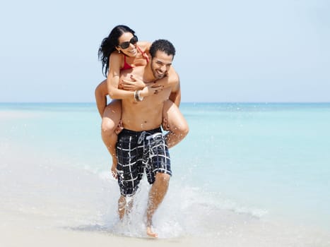 happy maried adult couple having fun and playing on the sea shore in cuba. Horizontal shape, full length, copy space