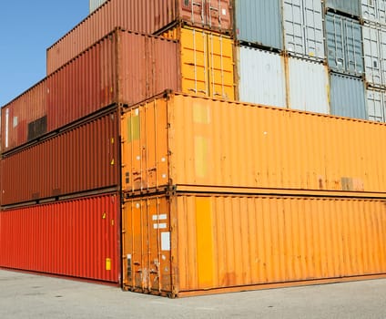 Cargo shipping containers stacked at harbor freight terminal under clear blue sky