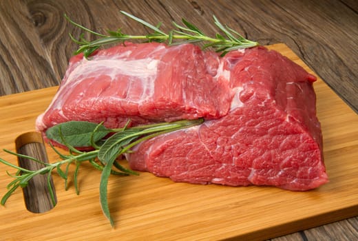 red meat with pepper and rosemary on wooden board