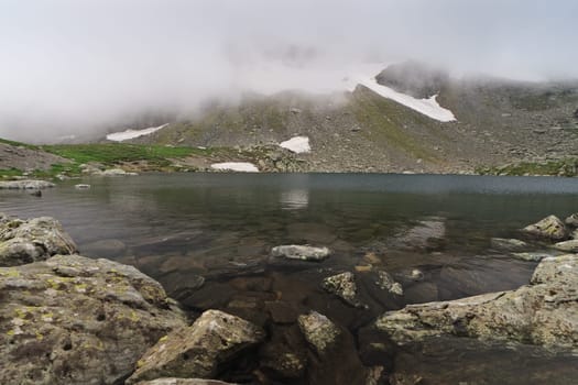 snow and fog near a mountain lake