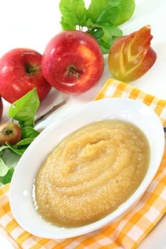 a white bowl with applesauce and fresh apples