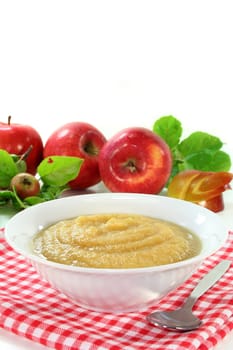 a white bowl with applesauce and fresh apples