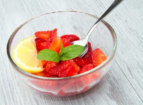 Strawberries in a cup decorated with a lemon on white background