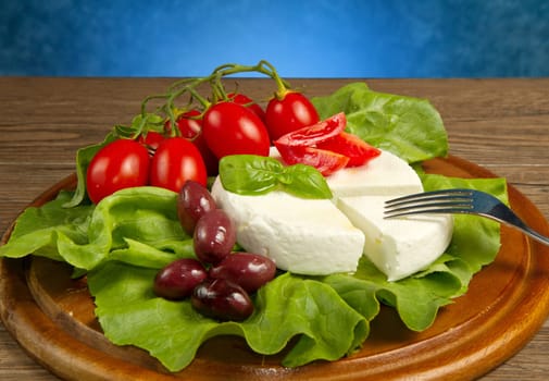 fresh cheese with salad, tomatoes and black olives