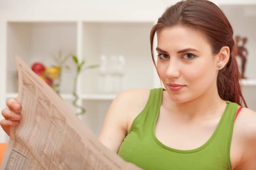 young woman holding newspaper sitting on sofa
