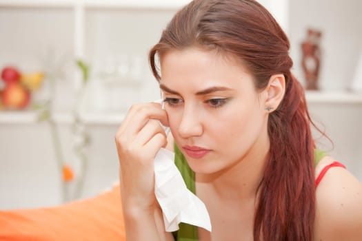 sad woman with handkerchief crying on sofa