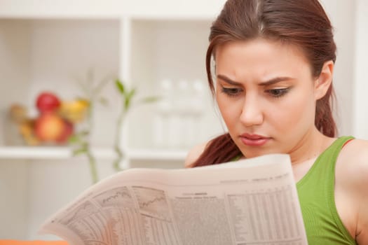 young woman reading bad news in newspaper at home