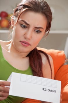 shocked woman holding bill or invoice at home