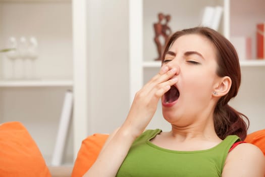 yawning woman sitting on sofa at home