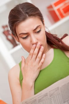 shocked woman reading bad news in newspaper