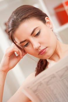 young woman reading business newslater at home