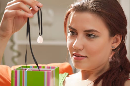 young woman holding a chain with stone from gift box