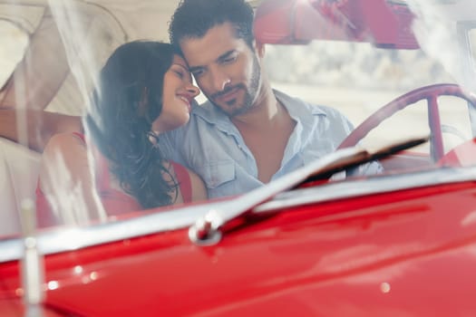 young happy man and woman dating in red convertible vintage car from the 50s in havana, cuba. Horizontal shape