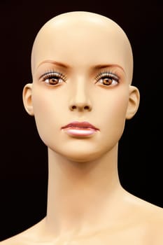 Face of a bald mannequin isolated on black background