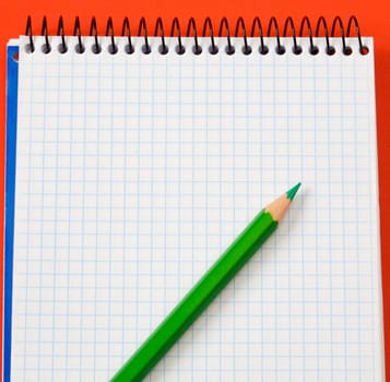 pencil and notebook over a red background