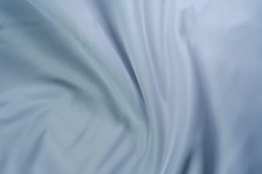 Close-up of soft white fabric with gentle folds creating a swirl pattern, perfect for backgrounds, textures, and design projects.