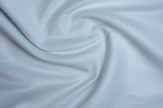 Close-up of soft white fabric with gentle folds creating a swirl pattern, perfect for backgrounds, textures, and design projects.