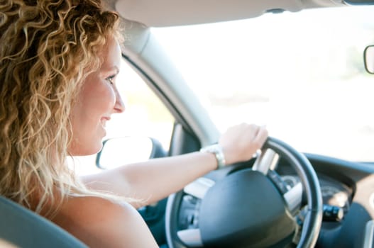 Portrait of young smiling woman driving car