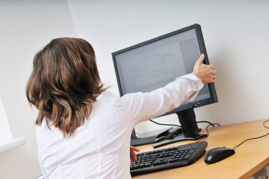 Business person (young woman) adjusting computer monitor - office interior