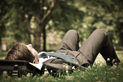 Senior people series - mature business man lying on grass and relaxing in green park