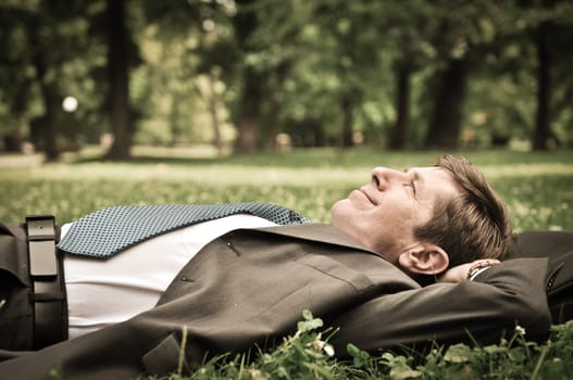 Senior people series - mature business man lying on grass and relaxing in park