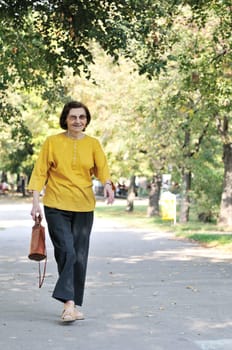 Energic and smiling "80 something"" senior woman wlaking in park on sunny day"