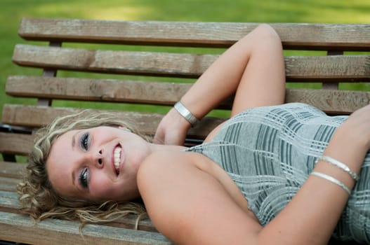 Smiling woman lying on bench outside