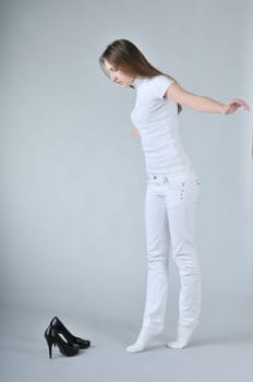 Young woman balancing on toes with high heels shoes placed on floor