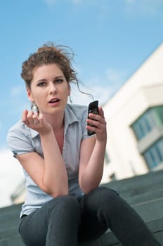 Young beautiful woman holding mobile phone with question in her expression