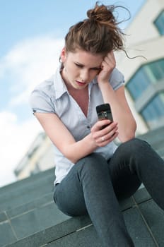 Young unhappy woman typing on mobile phone - outdoors in street