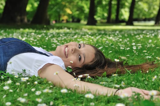 Detail of young woman lying in fresh green grass with flowers - above view
