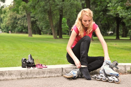 Young woman taking on roller skates - outdoors in park