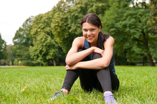 Relax - sportswoman sitting in grass
