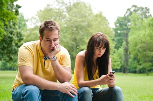 Young couple sitting outdoors on bench having relationship problems