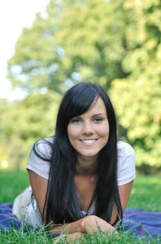 Beautiful young happy smiling woman lying in grass outdoors with copy space
